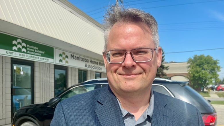 A man standing in front of the office for the Manitoba Home Builders Association.