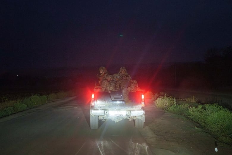 Ukrainian soldiers are seen riding in the back of a pickup truck on Wednesday, en route to their positions along the front line in the Donetsk region.