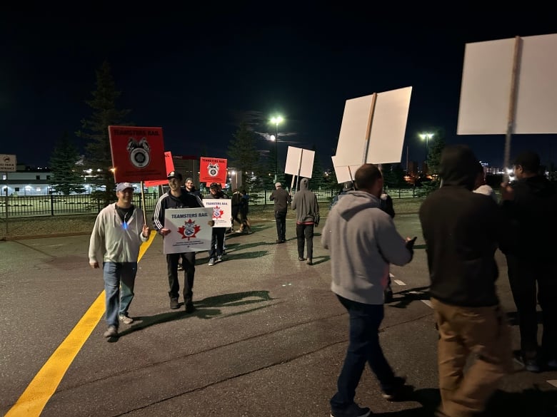 Several people walking around holding picket signs.