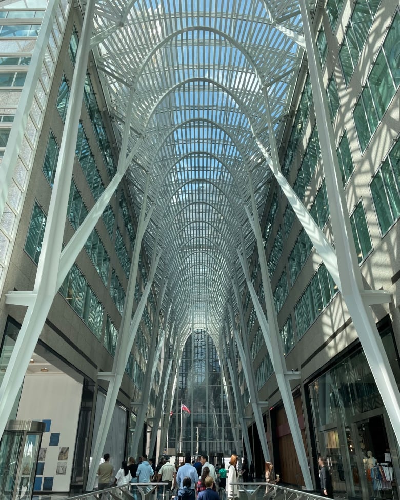 Daytime photo of the Allen Lambert Galleria at Toronto's Brookfield Place. It is a towering atrium framed by rows of white parabolic arches. A crowd bustles below.