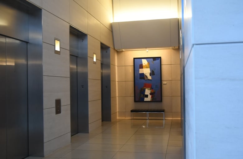 A boldly coloured hardline abstract painting hangs in a coporate elevator lobby.