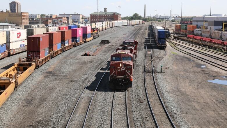 A red train engine moves along a rail line. 