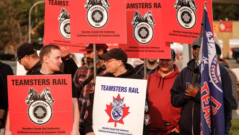 Rail workers hold up picket signs