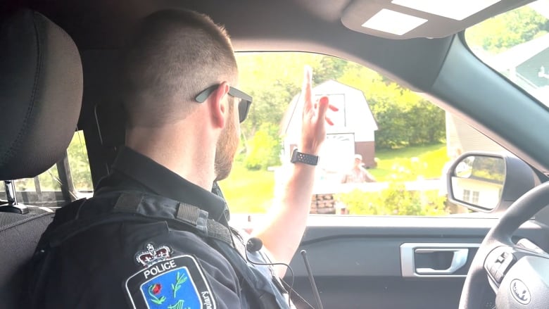 A police officer waves out the window of his patrol car.