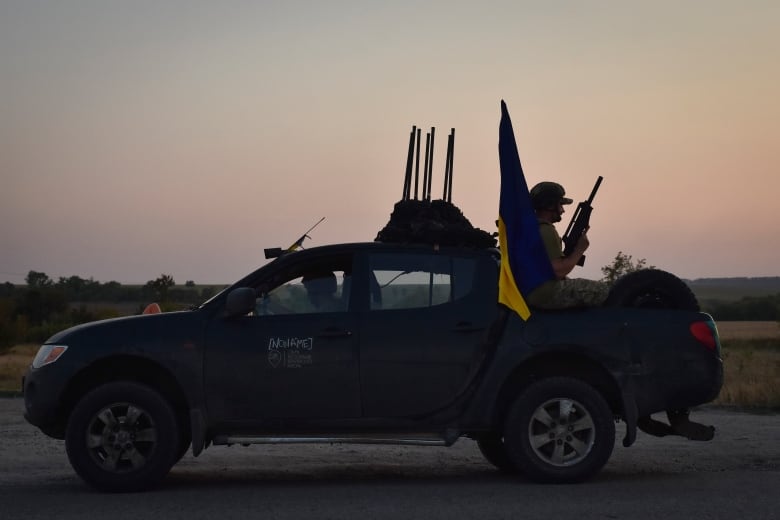 A Ukrainian solider is seen riding in the back of a pickup truck in Ukraine's Zaporizhzhia region on Monday.