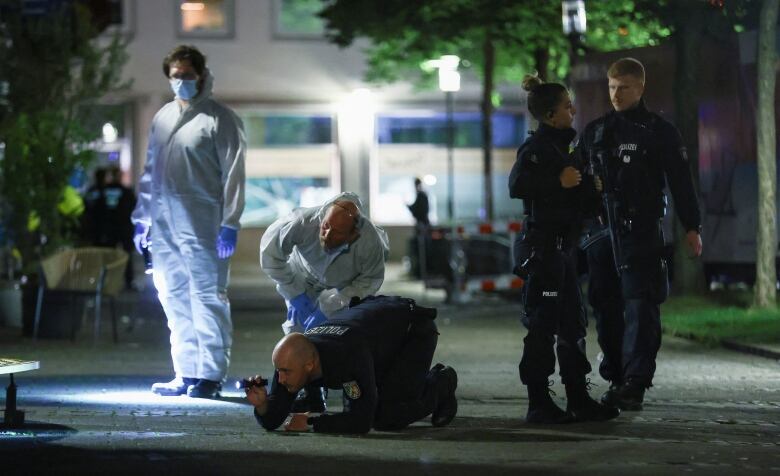 Police officers and forensic staff examine a scene at a festival in western Germany where at least three people were fatally stabbed on Friday.