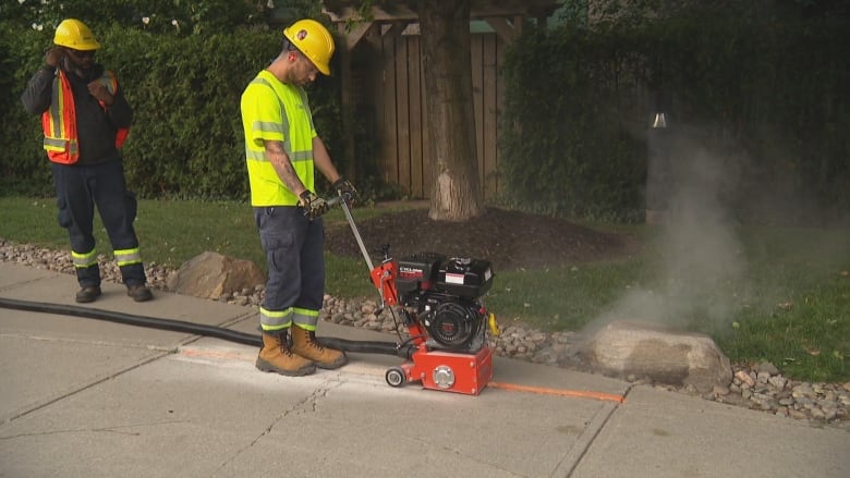 A worker uses a concrete grinder to repair a sidewalk.