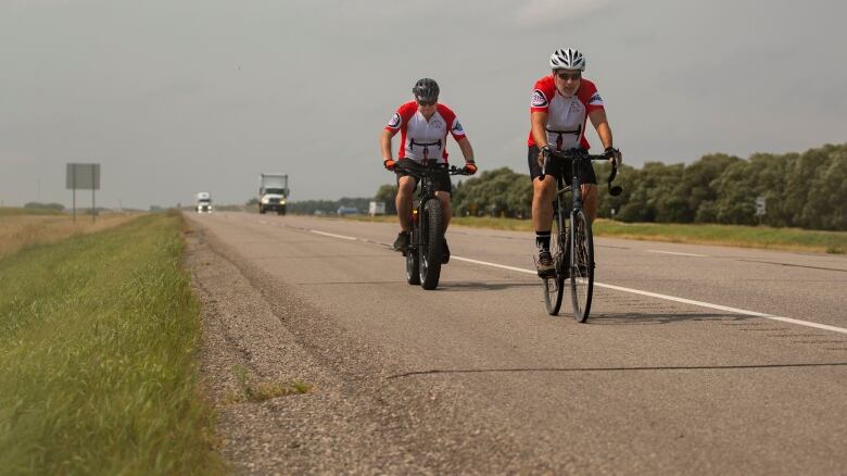 Two men cycle on a highway.