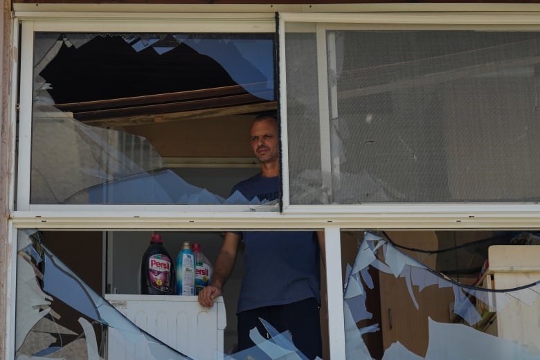 A man looks out a broken window.