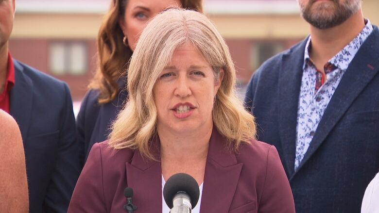 A woman with blond hair speaking into a microphone