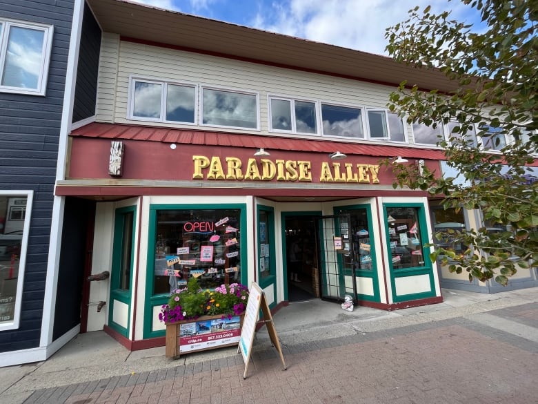 A white wood pannelled store front with a red awning and gold letters spelling 