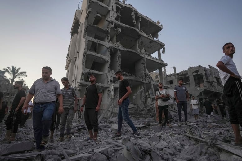 People walk near the ruins of a building destroyed in an airstrike. 