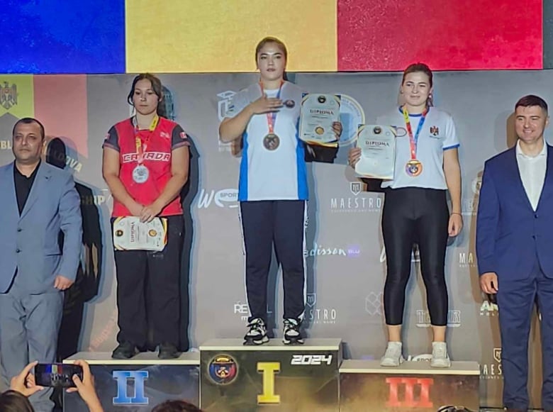 Three woman stand on a medal podium