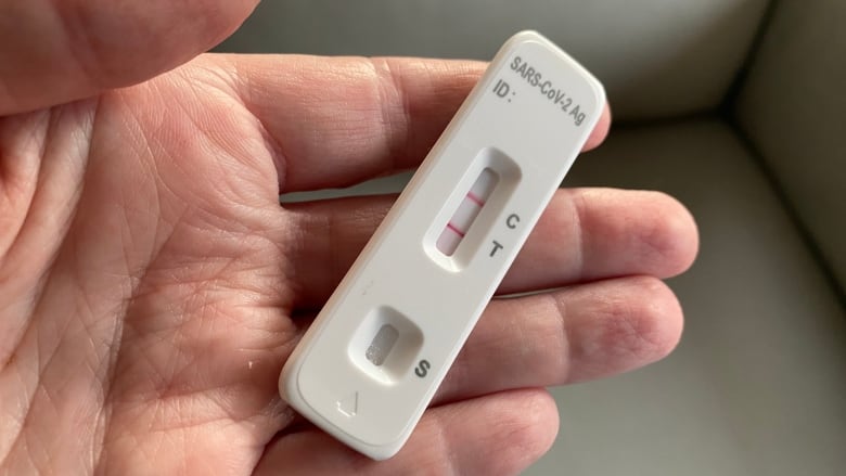 Closeup of a hand holding a positive COVID 19 test in March 2024.