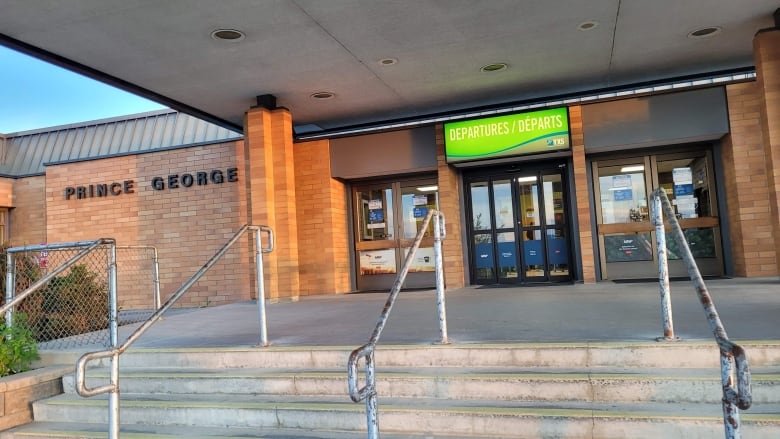 A set of stairs going up to a brick building with signage reading 