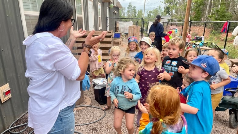 Woman speaking to a group of kids outside.