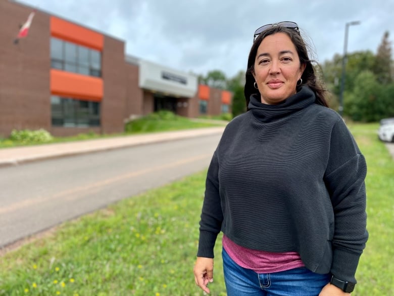 Woman in black sweater standing outside a school.