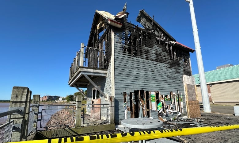 Two-storey, red-roofed building heavily damaged by fire. 