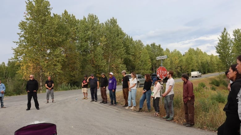 People stand in a row on a road.