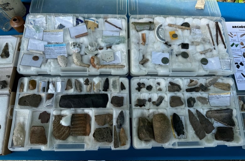 Small artifacts such as arrowheads, pipes and pottery fragments laid out on a table.