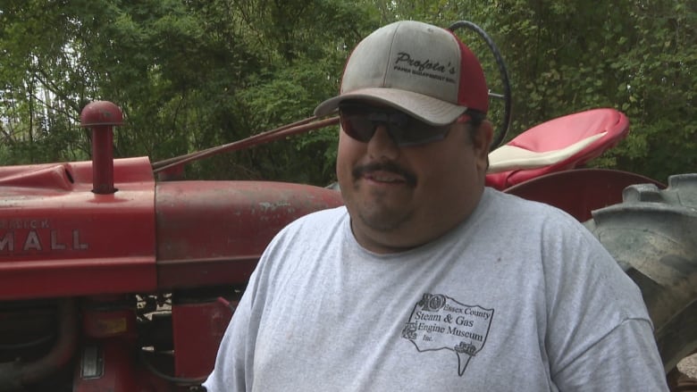 Close-up of a man in a ball cap standing in front of a tractor.