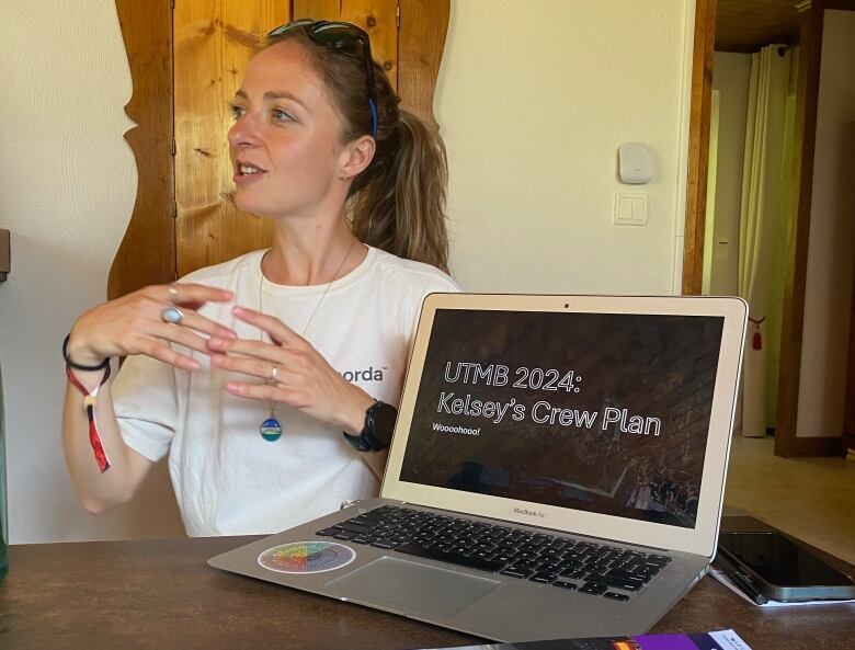 A woman talking beside a open laptop that reads 