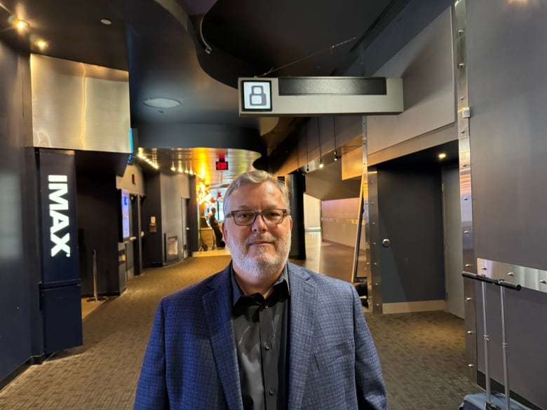 A man stands in a movie theatre hallway.