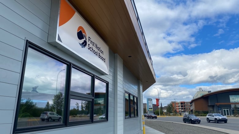 the exterior or a grey building with an orange sign for the The First Nation School Board 