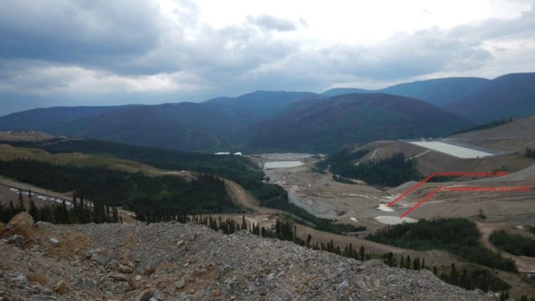 A view of mountains and a mine site, with red arrows drawn on the image.