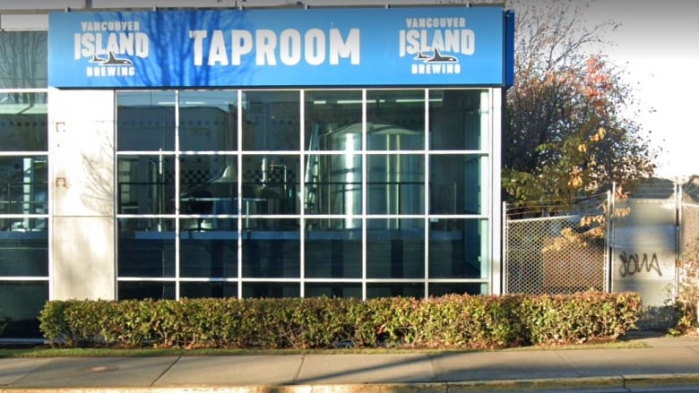 A brewery with tanks visible through its glass windows photographed from the street. 