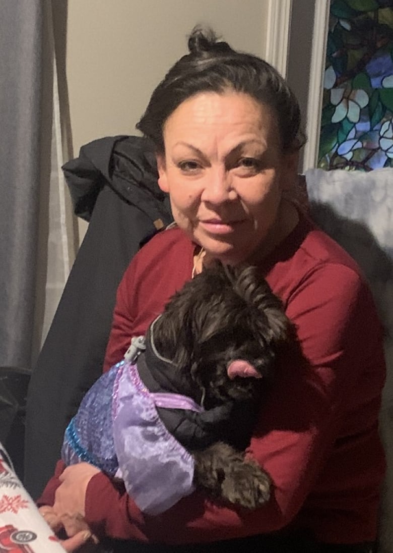 A woman in her 50s holds a dog.