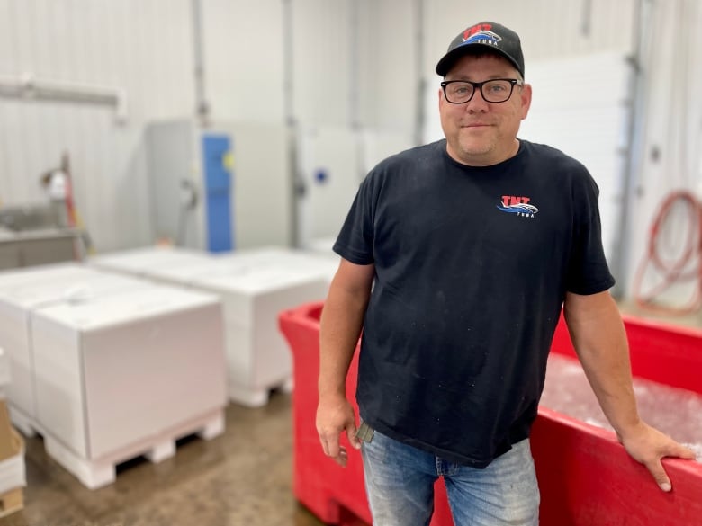 Jason Tompkins, owner of TNT Tuna, stands at his facility in North Lake, wearing a TNT Tuna hat and t-shirt. 