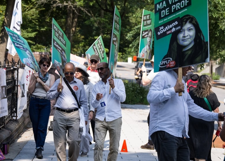 Professors striking, holding green signs. 