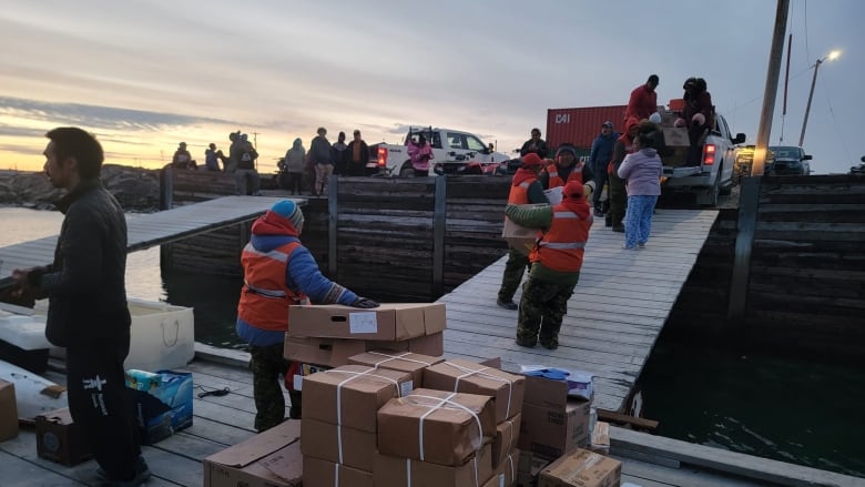 Volunteers move boxes from boat ramp to trailers. 