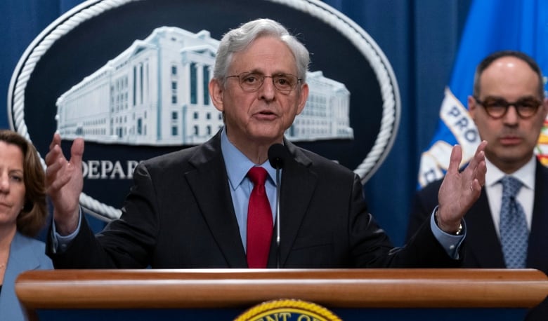 A man gestures while at a podium. 