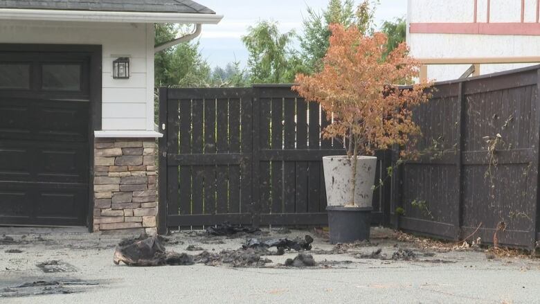 Charred vehicle remains on a driveway.