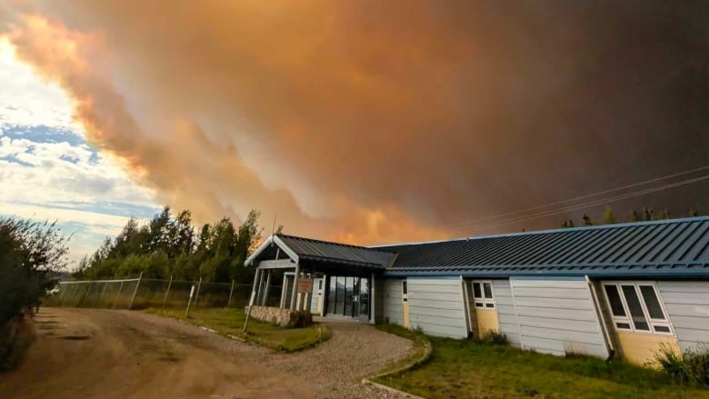 a wide blue building with smoke billowing behind it