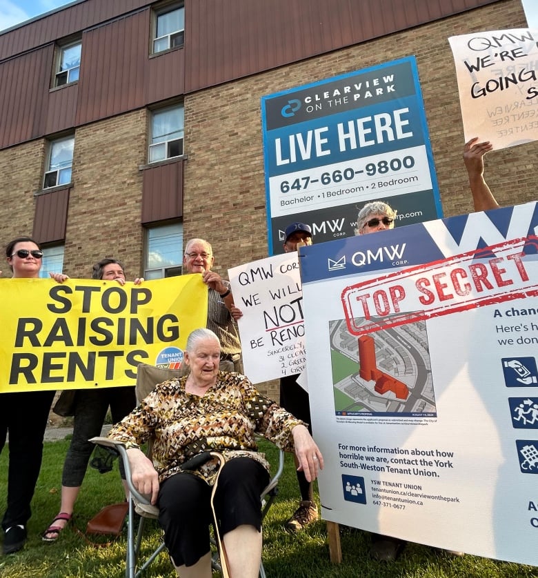 Tenants holding signs in front of apartment building against raising rents.