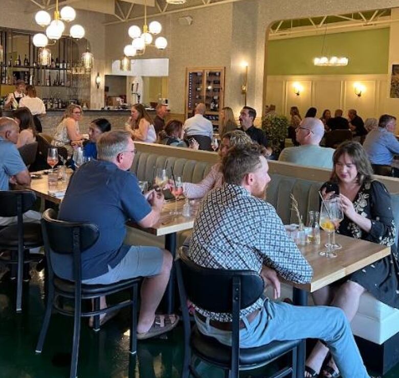 Customers sit at intimate tables in a restaurant with a green floor.