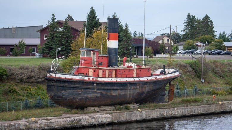 A tug boat in dry storage along a river.