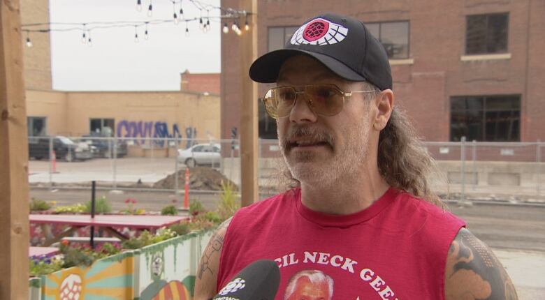 Man is his '50s stands outside with construction going on behind him.