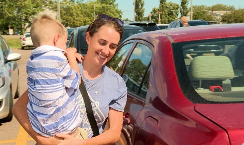 Woman carrying child in parking lot.