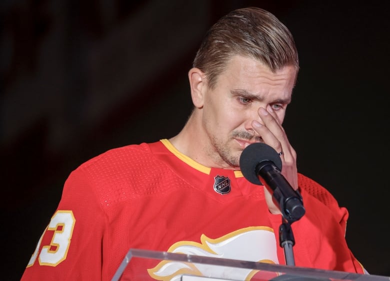 A man in a red jersey wipes tears from his eyes. 