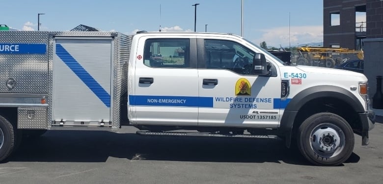 A white truck owned by Wildfire Defense Systems is emblazoned with the company's logo and is marked as 