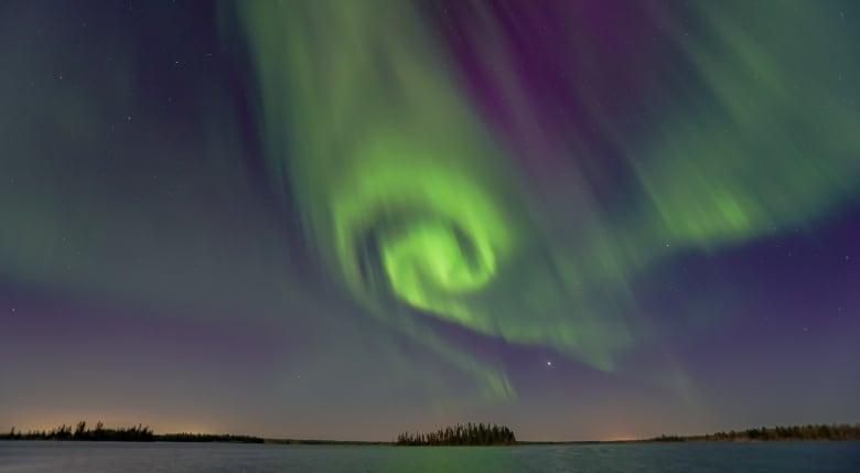 A nighttime shot of a green and purple and blue sky with the island in the middle.