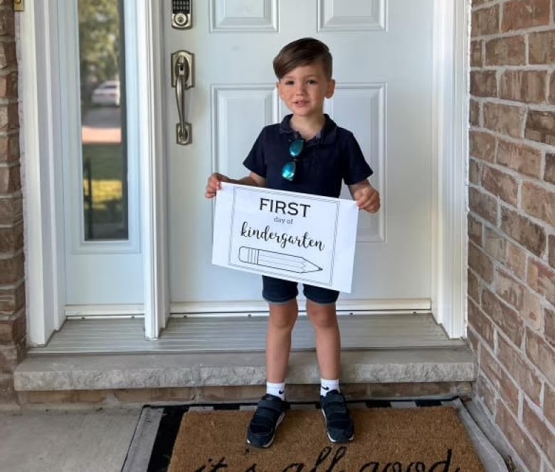 A little boy holds a sign that says first day of kindergarten