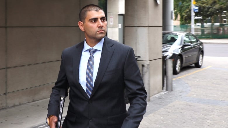 man in suit walks outside courthouse