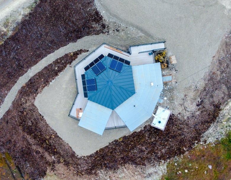 An aerial view of Kuugalaaq in Cambridge Bay, Nunavut shows the building's hexagonal shape. The space includes a central gathering room with a few other rooms, such as a kitchen and meeting room, surrounding it. 