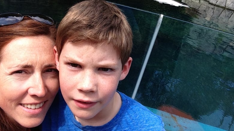 A woman and child take a selfie in front of a pool in a zoo.