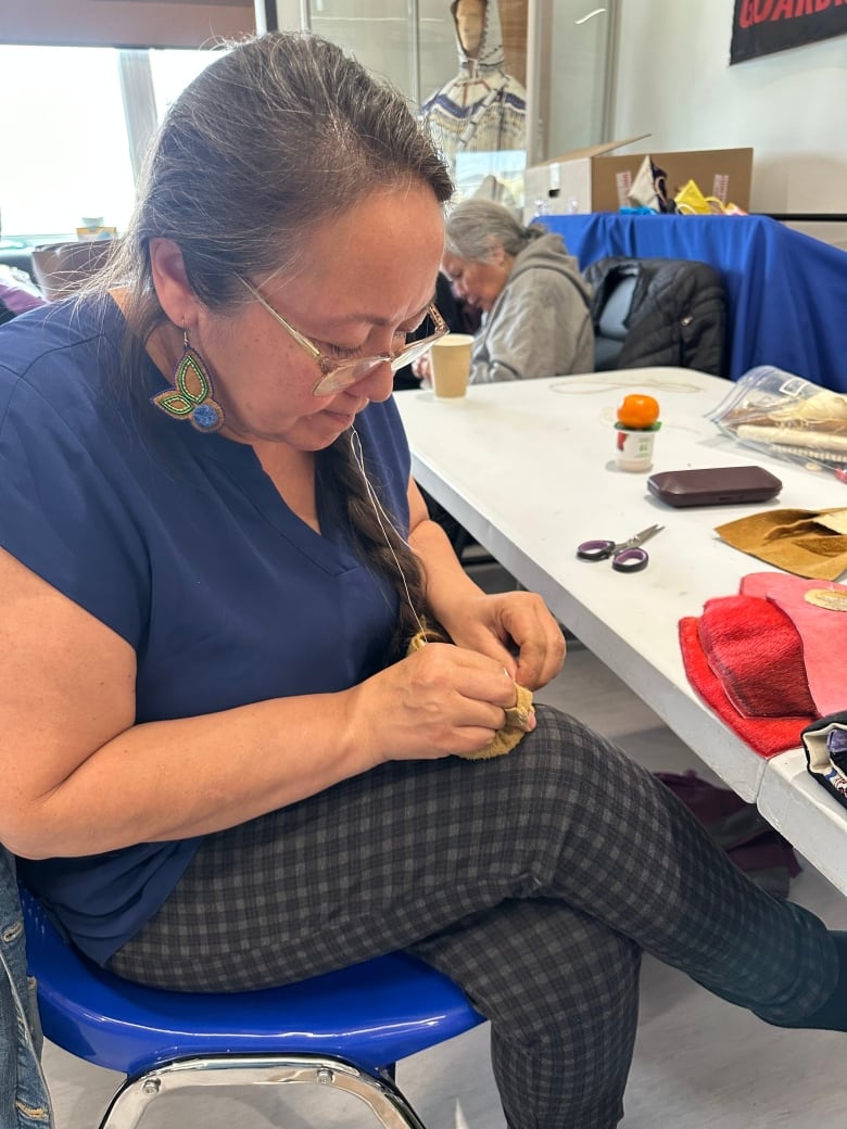 A woman looks intently at something she is sewing.